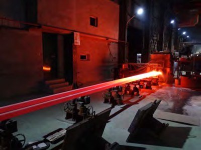 Continuous casting line producing red-hot ductile iron bar next to a sand casting foundry floor